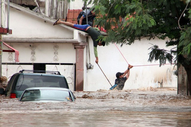 Một nhân viên cứu hộ bám vào dây để giúp đỡ các nạn nhân mắc kẹt trong nước lũ ở Chailpanchingo, Mexico.