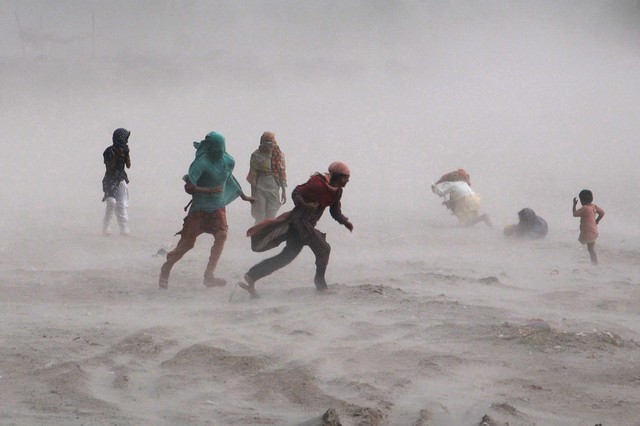 Mọi người cố gắng di chuyển trong một trận bão cát ở gần sông Ravi ở Lahore, Pakistan.