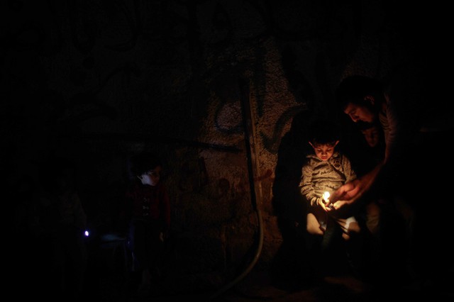 Trẻ em thắp nến ngồi trong bóng tối khi điện bị cắt trong trại tị nạn Jabalia ở thành phố Gaza.
