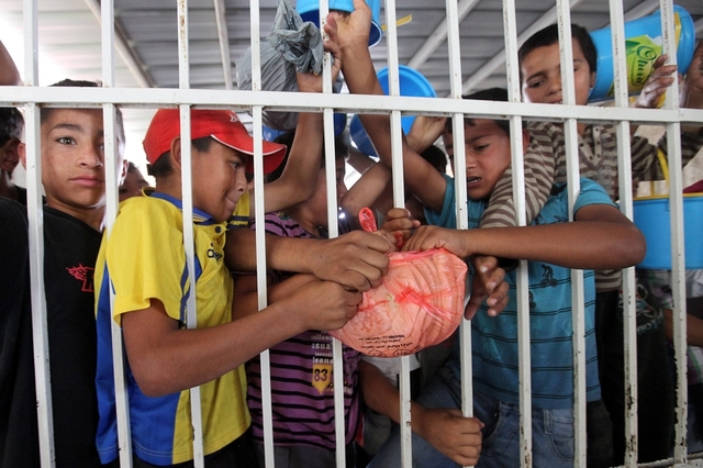 Các cậu bé người Palestin tranh nhau một túi đồ ăn miễn phí tại Hebron, Bờ Tây.