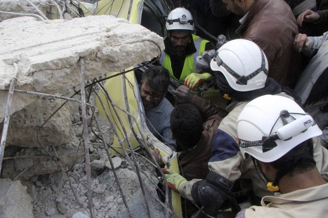 Mọi người giúp đỡ một nạn nhân sống sót ra khỏi đống đổ nát trong cuộc không kích ở Aleppo, Syria.