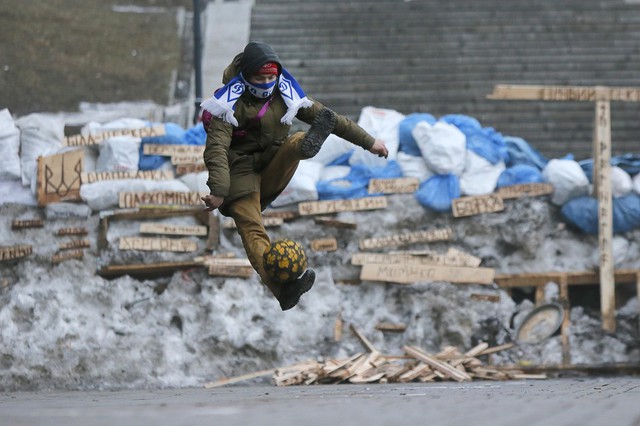 Một nhà hoạt động chơi bóng đá trước hàng rào chắn do người biểu tình xây dựng trên đường phố ở Kiev, Ukraine.