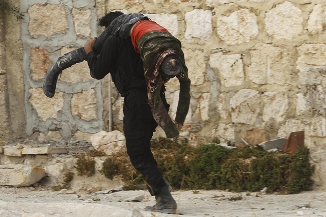 Một chiến binh phiến quân Syria vác xác đồng đội thiệt mạng trong cuộc đụng độ với quân đội chính phủ gần một sân bay ở thành phố Aleppo.