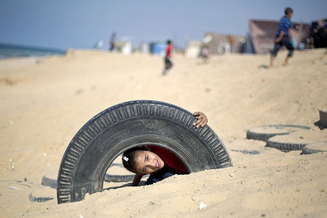 Một cậu bé người Palestin chơi với lốp xe ô tô trên bãi biển trong lễ hội Eid al-Adha của người Hồi giáo ở thành phố Gaza.
