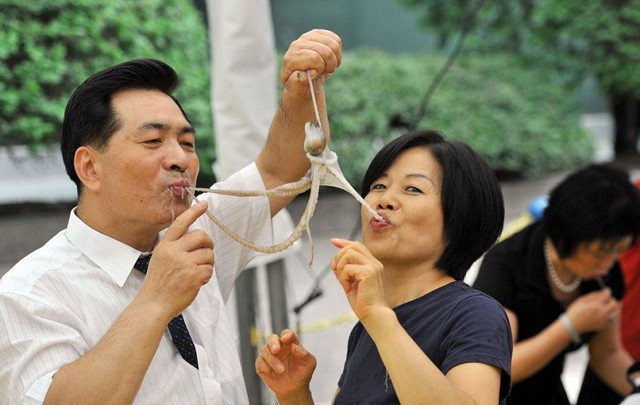 Một cặp đôi ăn mực sống tại một sự kiện quảng bá cho lễ hội ẩm thực ở Seoul, Hàn Quốc.