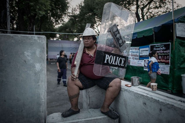 Một người biểu tình cầm khiên của cảnh sát và gậy ngồi gần tòa nhà quốc hội ở Bangkok, Thái Lan.