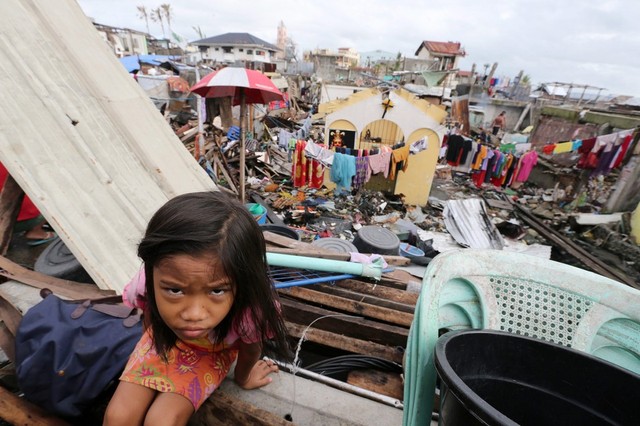 Bé gái Maureen Olendan, 8 tuổi, ngồi bên ngoài một ngôi nhà tạm tại thành phố Tacloban, Philippines.