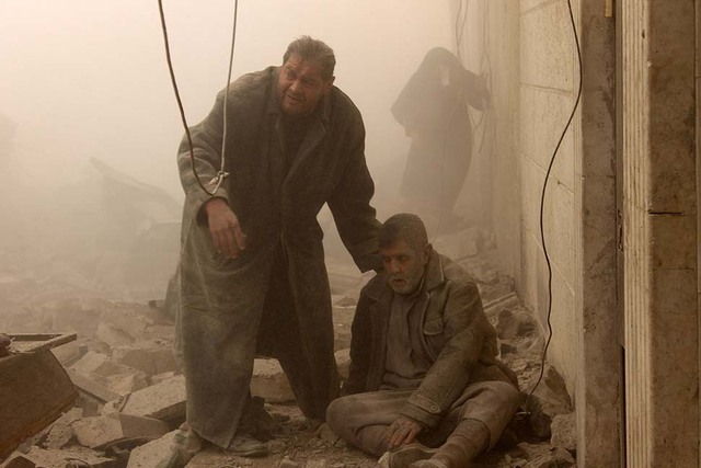 Một người đàn ông giúp đỡ những nạn nhân bị thương trong cuộc không kích tại thành phố Aleppo, Syria.