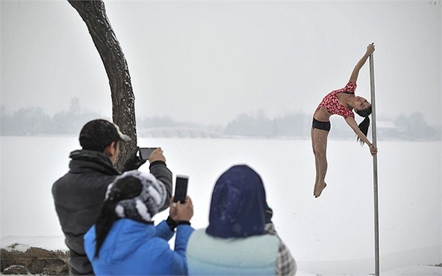 Thiếu nữ xinh đẹp của Đội múa cột quốc gia Trung Quốc biểu diễn trong trời mua tuyết ở Thiên Tân.