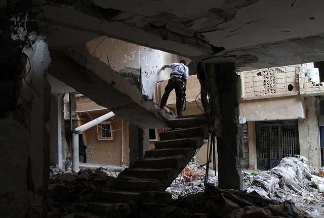 Chiến binh phiến quân Syria chiến đấu trong một ngôi nhà đổ nát ở Deir Ezzor.