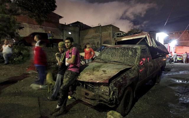 Mọi người đứng cạnh chiếc ô tô bị bao phủ đầy bùn đất sau khi mưa lớn gây lở đất ở Tegucigalpa, Mexico.