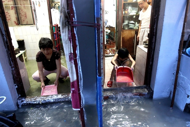 Người dân tát nước ra khỏi nhà sau trận mưa lớn tại một khu dân cư cũ ở Thượng Hải, Trung Quốc.