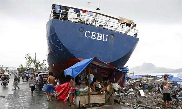 Một khu chợ tạm hình thành cạnh một con tàu lớn bị đánh dạt vào vờ sau siêu bão Haiyan ở thành phố Tacloban, Philippines.