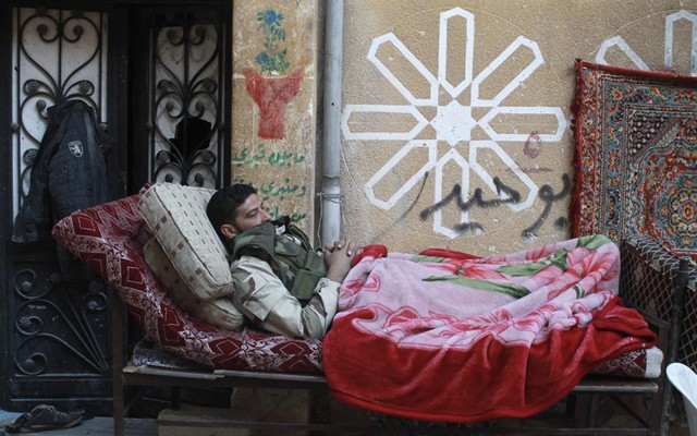 Một chiến binh phiến quân nằm nghỉ trên đường phố ở Aleppo, Syria.