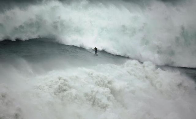 Một người đàn ông lướt ván trên con sóng lớn ở Praia do Norte, in Nazare, Bồ Đào Nha.