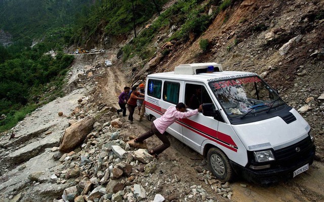 Mọi người đẩy một chiếc xe cứu thương qua đoạn đường bị sạt lở do mưa lũ ở Gauchar, Ấn Độ.