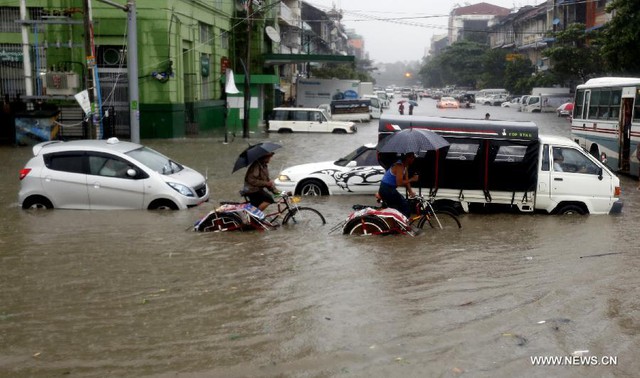 Mọi người và phương tiện di chuyển trên đường phố ngập lụt ở Yangon, Myanmar.