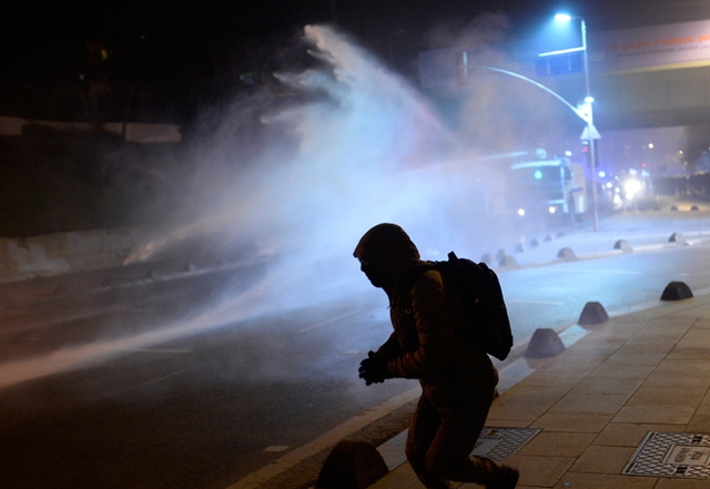 Một người biểu tình bỏ chạy khi bị cảnh sát chống bạo động xịt hơi cay và vòi rồng trong cuộc biểu tình chống tham nhũng ở Istanbul, Thổ Nhĩ Kỳ.