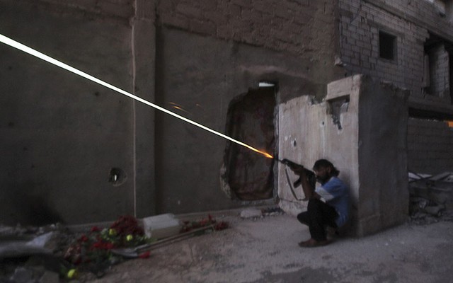 Một chiến binh của lực lượng phiến quân Syria xả đạn từ nơi ẩn nấp tại Deir al-Zor.