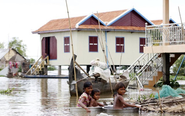 Trẻ em ngồi trong chậu để di chuyển trên nước lũ tại tình Kandal, Campuchia.