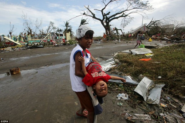 Một cậu bé vất vả bế em đang khóc giữa khung cảnh hoang tàn ở thành phố Tacloban.