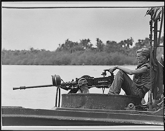 Một binh sĩ Mỹ ngồi sau súng máy trong khi tuần tra trên sông Gò Công. Chiến đấu trong rừng rậm với nhiều nguy hiểm đã khiến binh sĩ Mỹ bị các hội chứng chiến tranh.