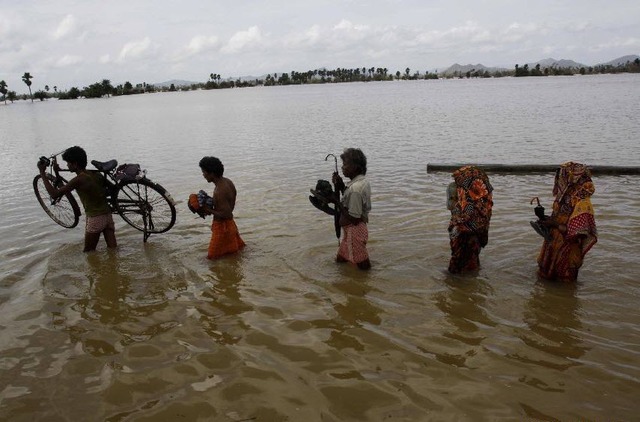 Người dân đi qua nước lũ ở Orissa, Ấn Độ.