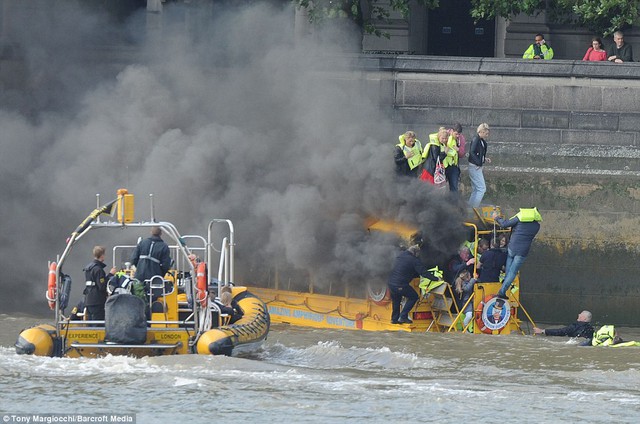 Smoking: Passengers are rescued from the roof of a smoking London Duck Tours amphibious vehicle by a speedboat on the River Thames, close to Westminster