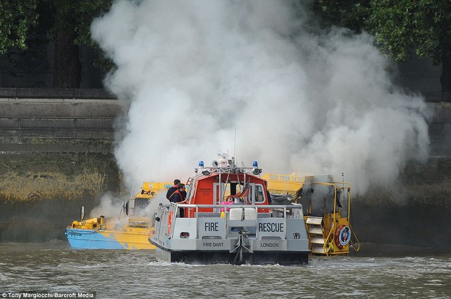 Responding: A London Fire Rescue boat approaches the smoking London Duck Tours amphibious vehicle on the River Thames, close to the Houses of Parliament