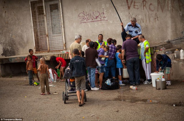 Clean water: Adults and children gather around a tap. The running water is cut off in most of the area and this tap, only available during certain hours, is monitored by the police