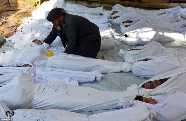 Một người đàn ông ôm thi thể trẻ em giữa xác của những nạn nhân thiệt mạng trong vụ tấn công bằng vũ khí hóa học ở ngoại ô thủ đô Damascus, Syria.