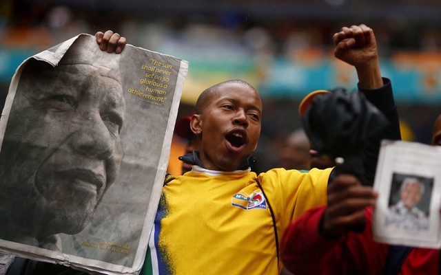 Một nam thanh niên cầm di ảnh của Nelson Mandela khi tới dự đám tang của ông.