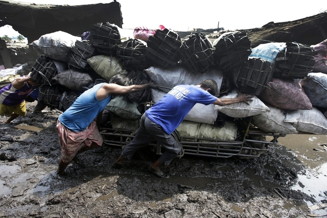 Công nhân đẩy xe chở các bao tải than củi tới bán tại một nhà máy thu mua ở Manila, Philippines.