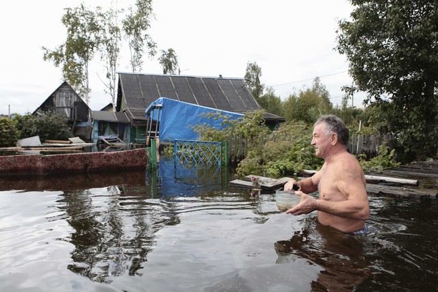 Một người đàn ông lội trong nước lũ để vào nhà của mình ở ngoại ô thành phố Khabarovsk, Nga.