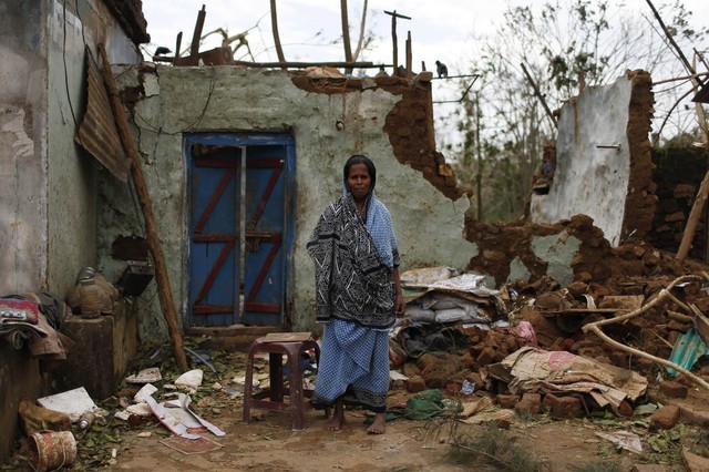 Một phụ nữ đứng bên ngoài bị phá hủy bởi lốc xoáy ở Gopalpur, Ấn Độ.