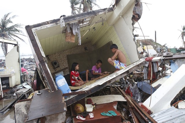 Trẻ em chơi trong phòng vệ sinh của một ngôi nhà bị lật do siêu bão Haiyan ở Tacloban, Philippines.