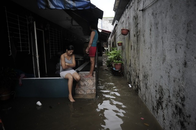 Những người dân đứng trước ngôi nhà bị ngập lụt do mưa lớn ở thành phố Panama City, Panama.