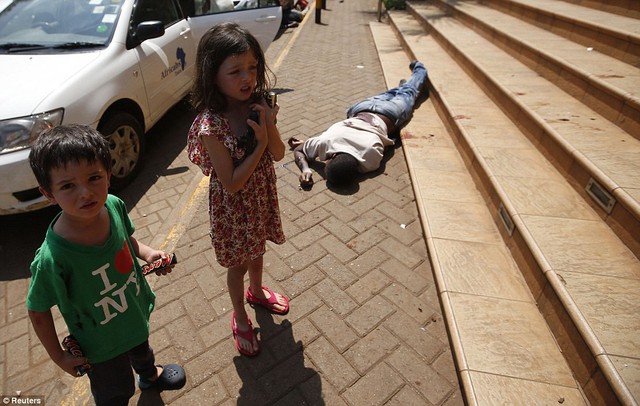 Những đứa trẻ hoảng sợ đứng chờ cạnh một thi thể người đàn ông, sau khi thoát trung tâm thương mại Westgate bị các phần tử khủng bố tấn công ở Nairobi, Kenya.