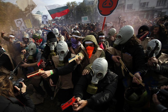 Sinh viên đeo mặt nạ phòng độc và cầm súng giả tham gia biểu tình tại Sofia, Bulgaria.