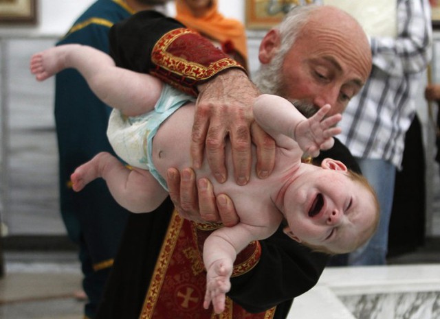 Một em bé chuẩn bị được gội đầu bằng nước thành trong lễ rửa tội tập thể tại nhà thờ Holy Trinity ở Tbilisi, Gruzia.