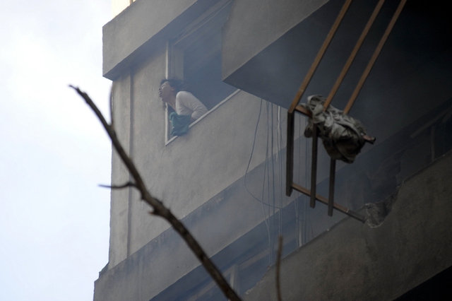 Một phụ nữ chạy ra cửa sổ để hít thở sau khi hít phải khói trong vụ nổ khí gas tự nhiên trên một căn hộ ở Rosario, Argentina.