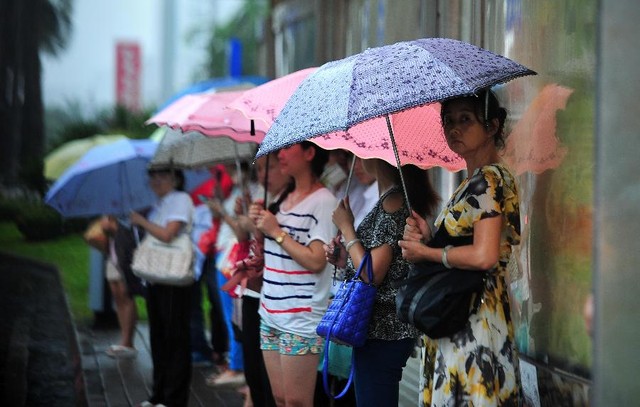 Mọi người chờ xe bus dưới trời mưa lớn ở thành phố Hải Khẩu.