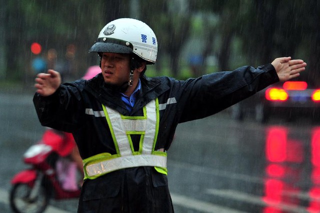 Cảnh sát giao thông làm việc dưới mưa lớn tại thành phố Hải Khẩu, tỉnh Hải Nam.
