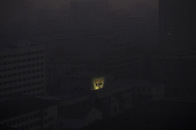 Bức chân dung của hai nhà lãnh đạo quá cố Kim Il Sung và Kim Jong Il được chiếu sáng giữa nhưng tòa nhà tối đen vào thời điểm rạng sáng ở thủ đô Bình Nhưỡng, Triều Tiên.