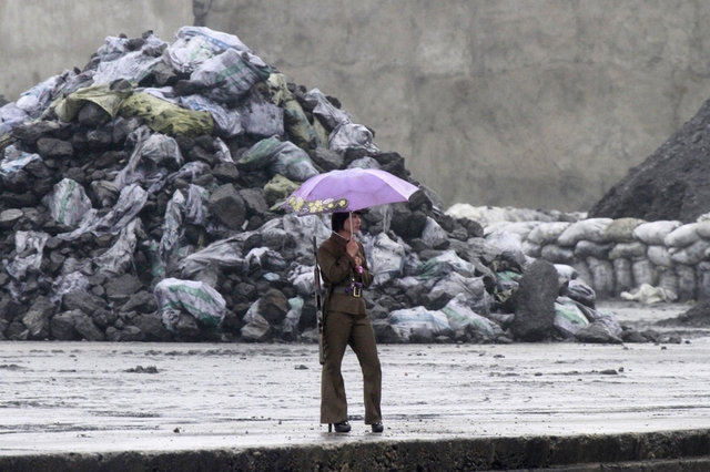 Nữ binh sĩ Triều Tiên cầm ô khi đứng canh gác trên bờ sông Yalu tại thị trấn Sinuiju gần biên giới với Trung Quốc.
