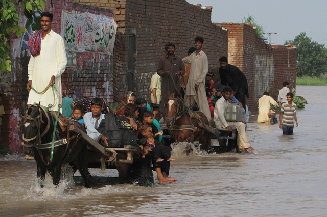 Người dân sơ tán khỏi khu vực bị ngập lụt sau nhiều ngày mưa lớn ở Kala Shah Kaku, gần Lahore, Pakistan.