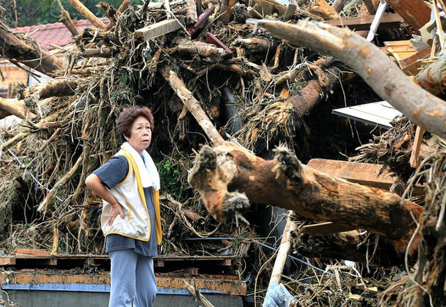  	Một người phụ nữ đứng bên cạnh hiện trường nơi bị cơn bão tấn công tại đảo Izu Oshima. Bão Wipha đã gây ra lở đất và khiến nhiều người tử vong trên hòn đảo này của Nhật Bản.