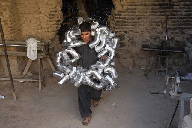 Một công nhân mang theo đường ống dẫn khí nóng ở Kandahar, Afghanistan.
