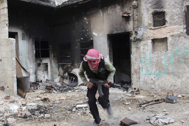 Một chiến binh phiến quân chạy tìm nơi ẩn nấp để tránh đạn bắn tỉa của quân chính phủ ở Aleppo, Syria.
