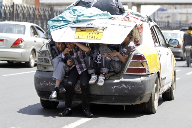 Các cậu bé thích thú ngồi sau một chiếc xe ô tô trên đường phố ở San’a, Yemen.
